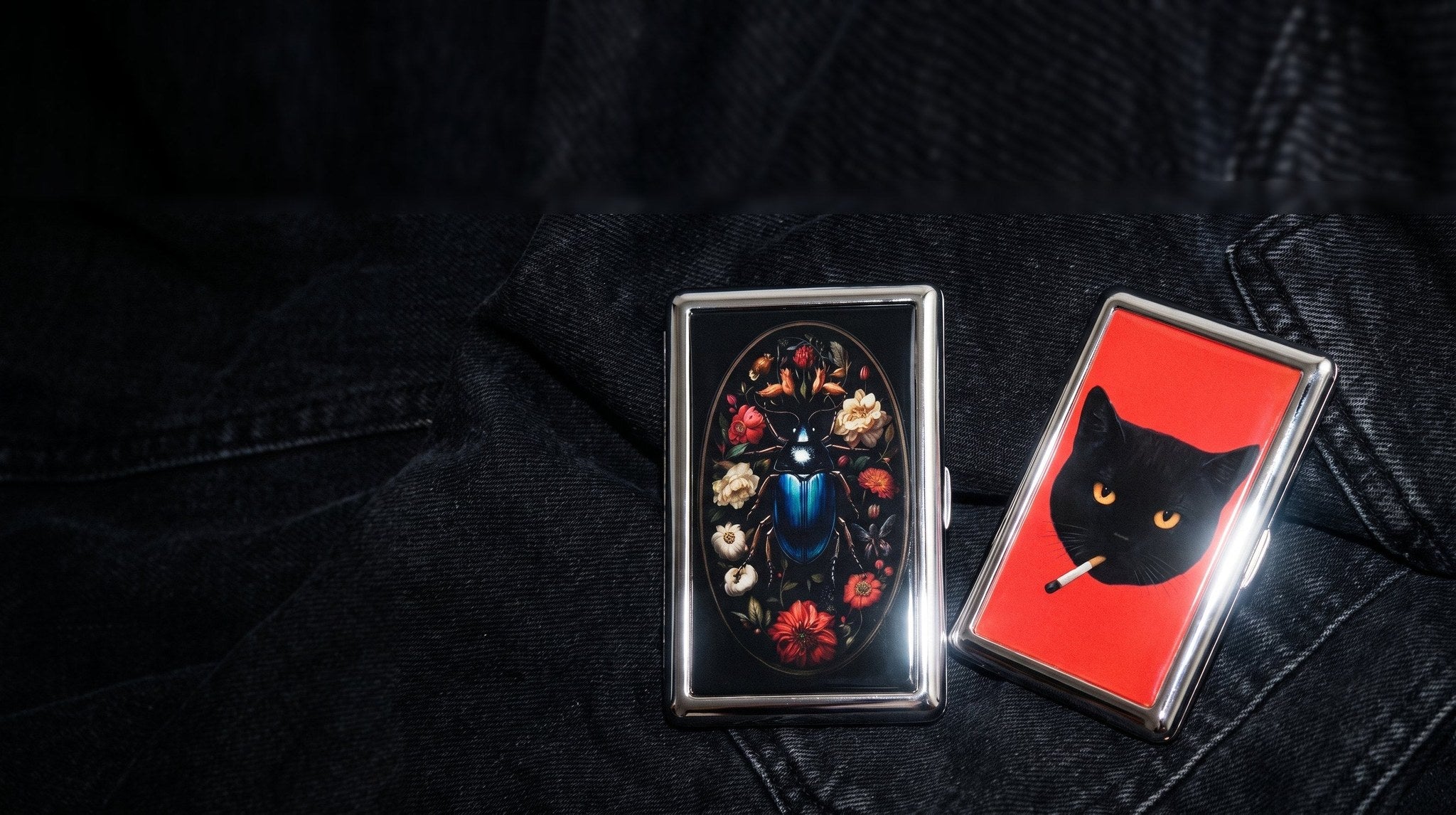 Two chrome tin wallets on black denim, night flash macro